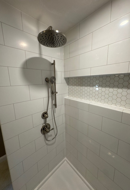 An elegant bathroom got remodeled with a modern showerhead, surrounded by sleek tile in Franklin, MA